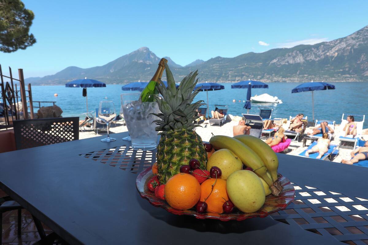 Une table avec un panier de fruits, un verre d’eau et une bouteille de champagne.