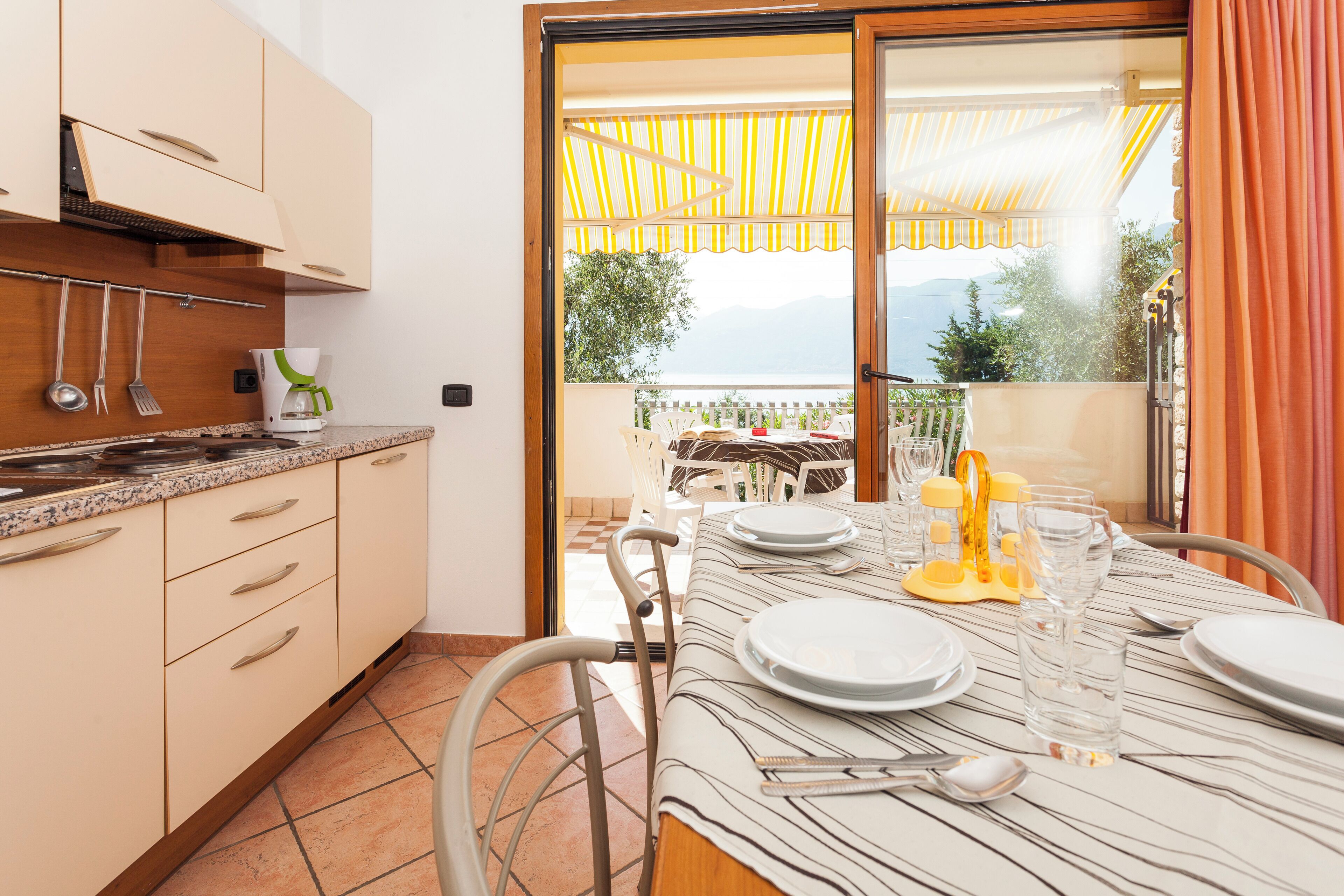 Een moderne keuken met een eetgedeelte, met een grote schuifglazen deur naar een balkon met uitzicht op de bergen.