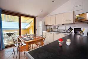 Een moderne keuken met een eethoek, met een groot kookeiland, een inbouwoven en een televisie boven het aanrecht.