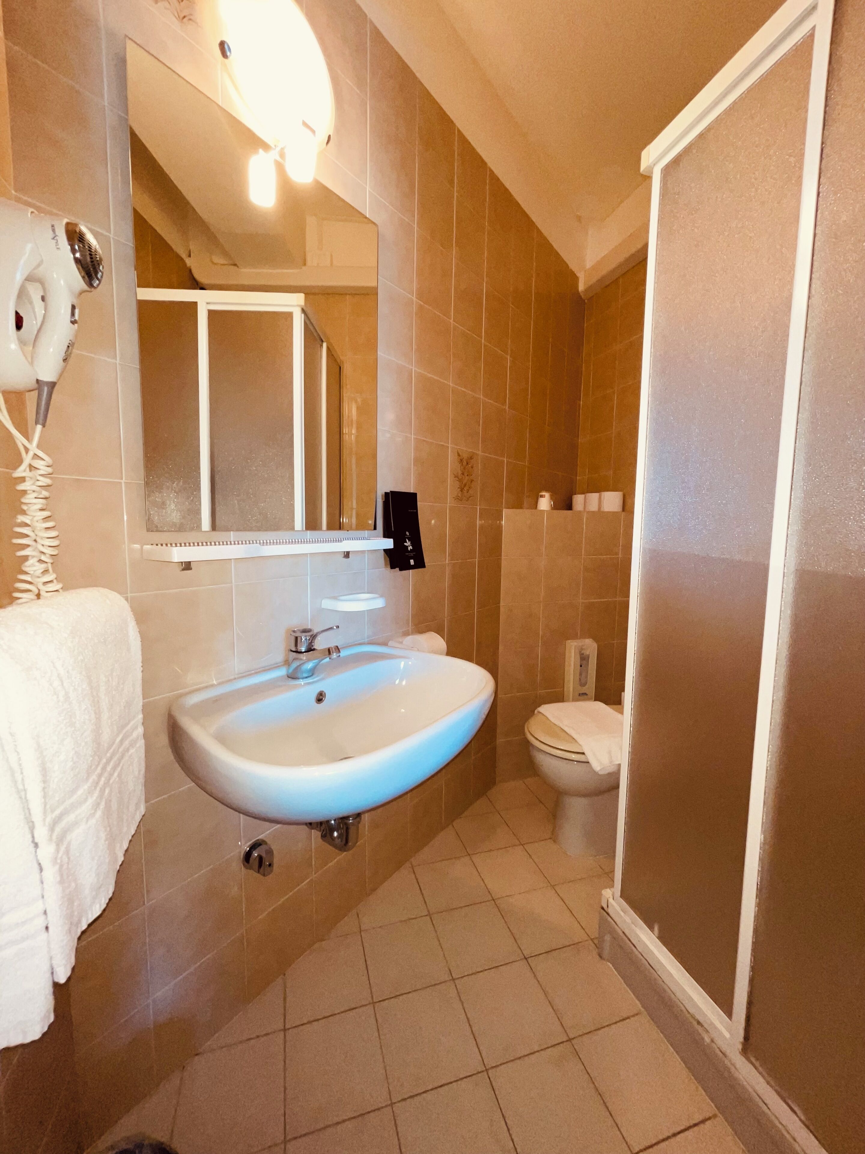 Un baño con lavabo, espejo, secador de pelo y retrete.