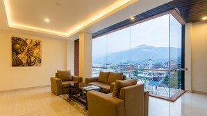 Amplia sala de estar con un ventanal que ofrece vistas a la ciudad, un conjunto de sofás modernos y una estatua de Buda en la pared.