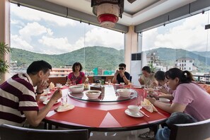 Un groupe de personnes est assis autour d’une table ronde en verre, et la table est décorée de sets de table rouges et de différents plats.