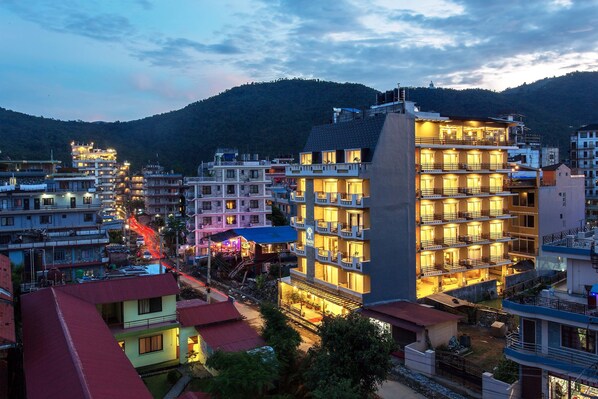 Un hôtel à plusieurs étages, doté de balcons et offrant une vue sur un paysage montagneux.