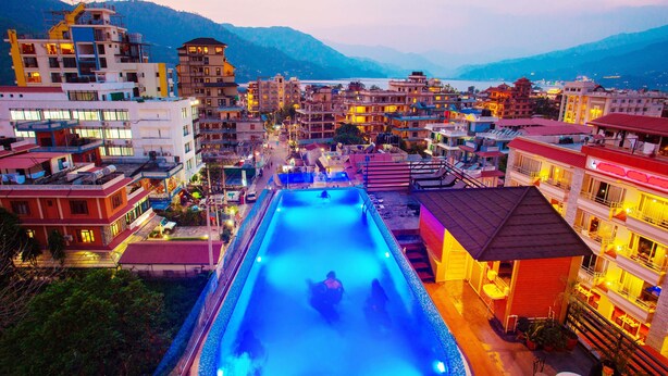 Un hotel con piscina, varios pisos y un paisaje montañoso.