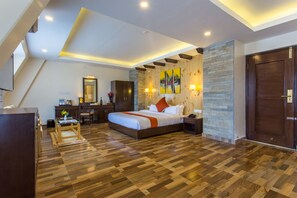 Une chambre à coucher moderne avec un grand lit, un plancher en bois, un mur d’accent en pierre et une porte en bois foncé.