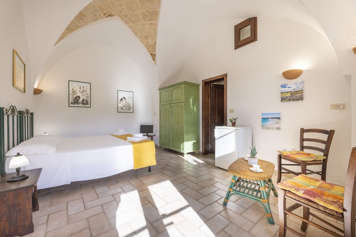 Une chambre à coucher avec un lit, un bureau, une chaise et une armoire verte.