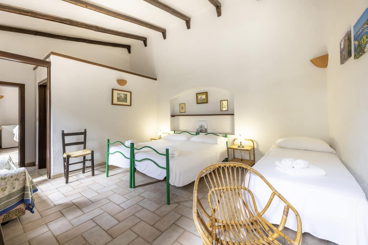 Une chambre à coucher comprenant un lit, une chaise, une table de chevet et un mur orné de tableaux.