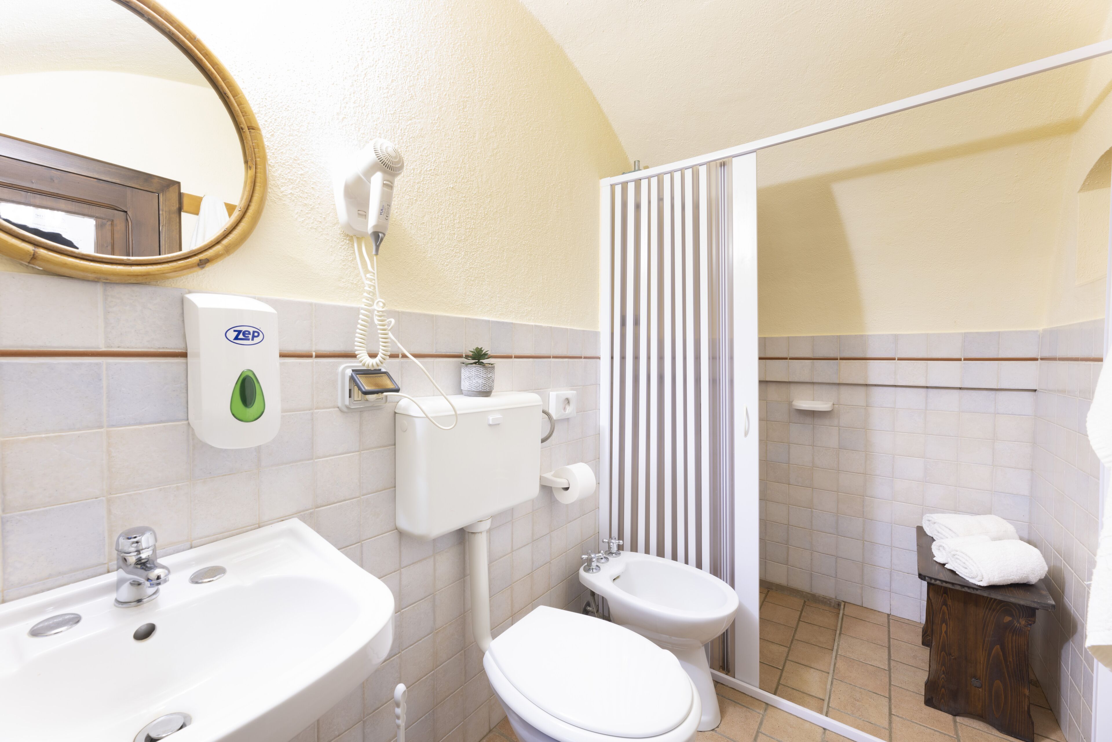 A bathroom with a sink, toilet, bidet, and a shower area.
