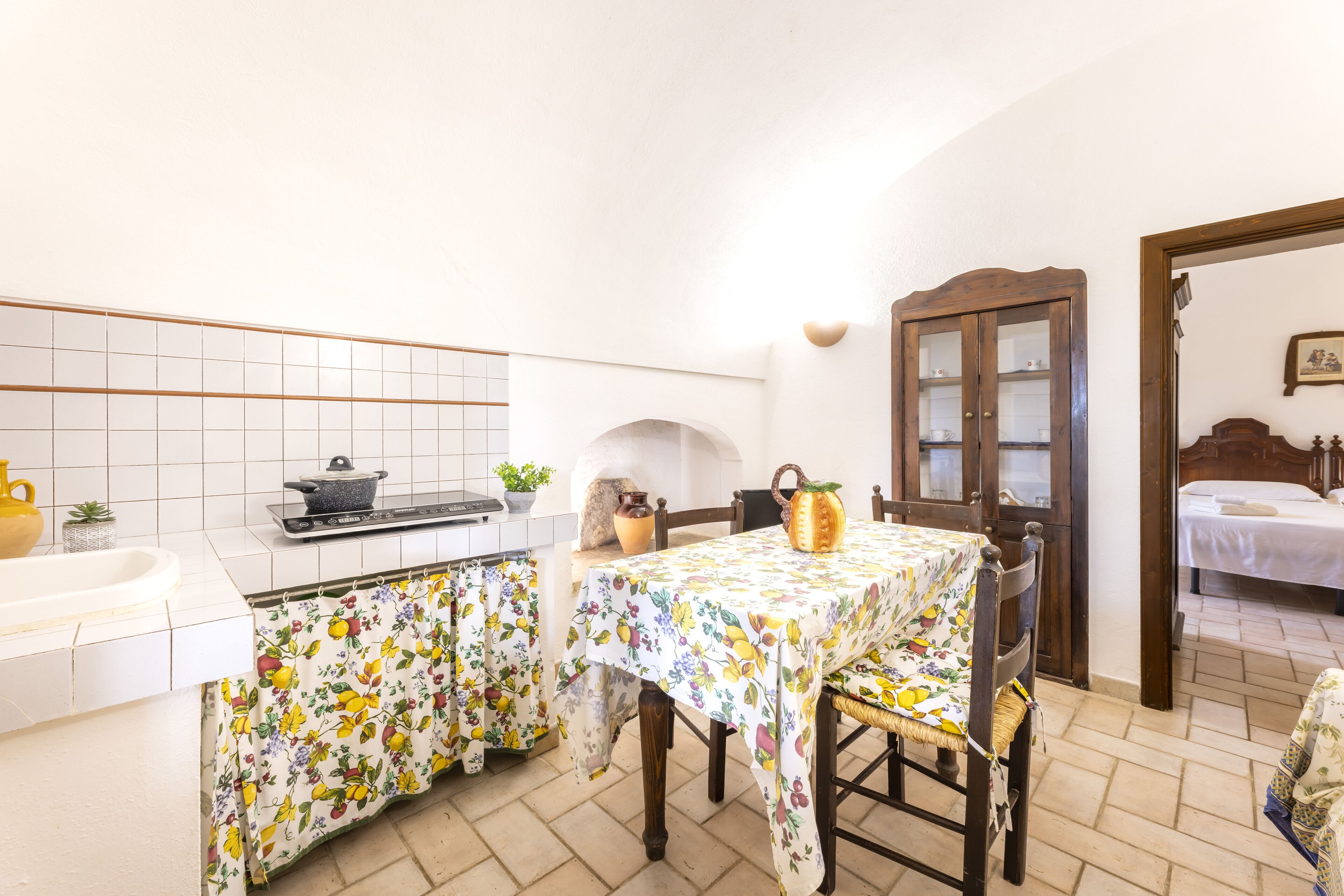 Een compacte keuken met witte tegels, een spoelbak en een eethoek met een tafel en stoelen.