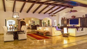 A spacious living area with a high ceiling, exposed wooden beams, a dining area with a table and chairs, and a seating area with sofas and a coffee table. - Casa Mar by Cabo Platinum (Cabo San Lucas)
