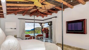 A spacious bedroom with a large bed, a ceiling fan, a TV mounted on the wall, and a view of the ocean through the window. - Casa Mar by Cabo Platinum (Cabo San Lucas)