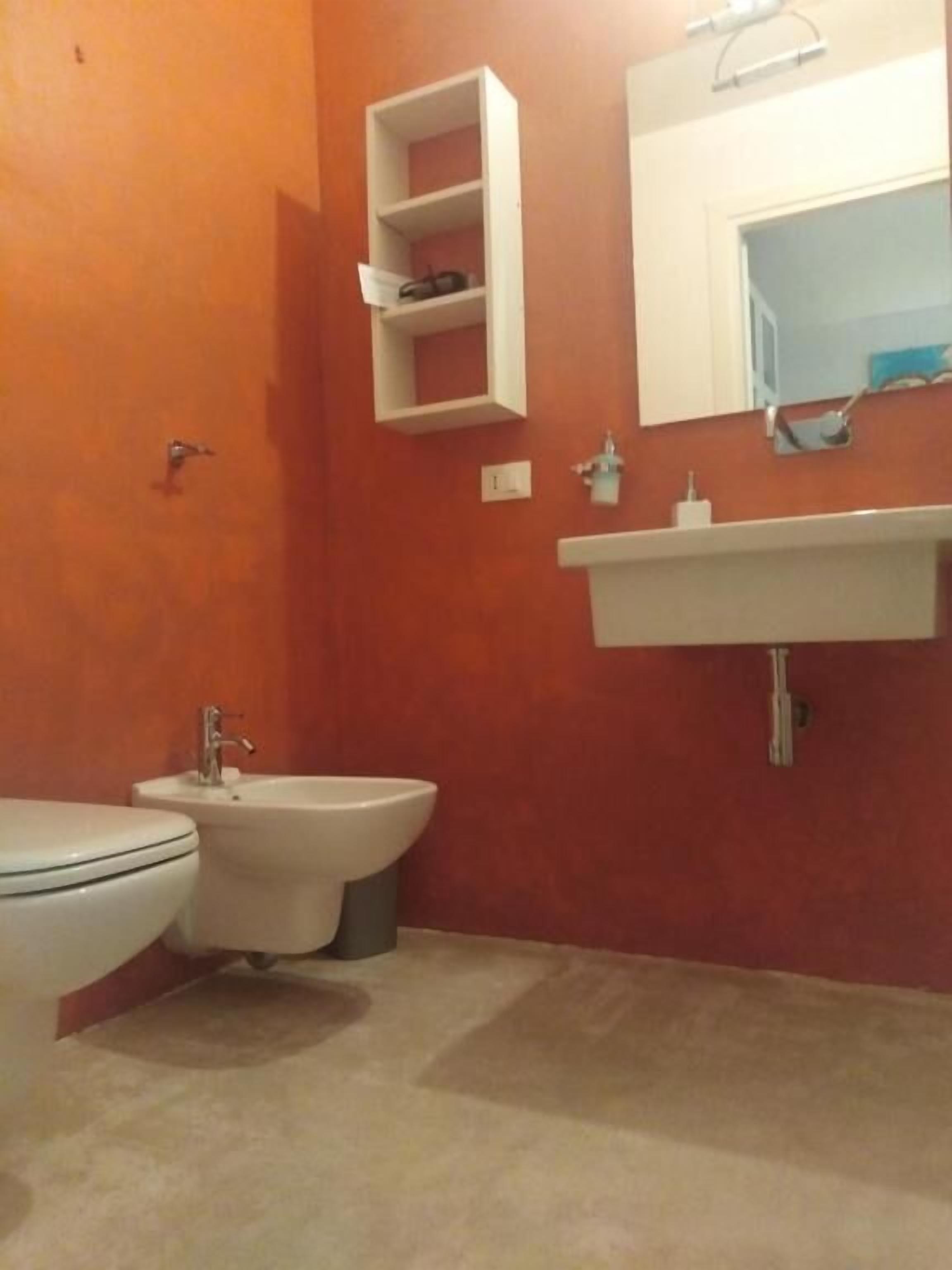 Casa de banho com sanita, bidé e lavatório com espelho em cima.