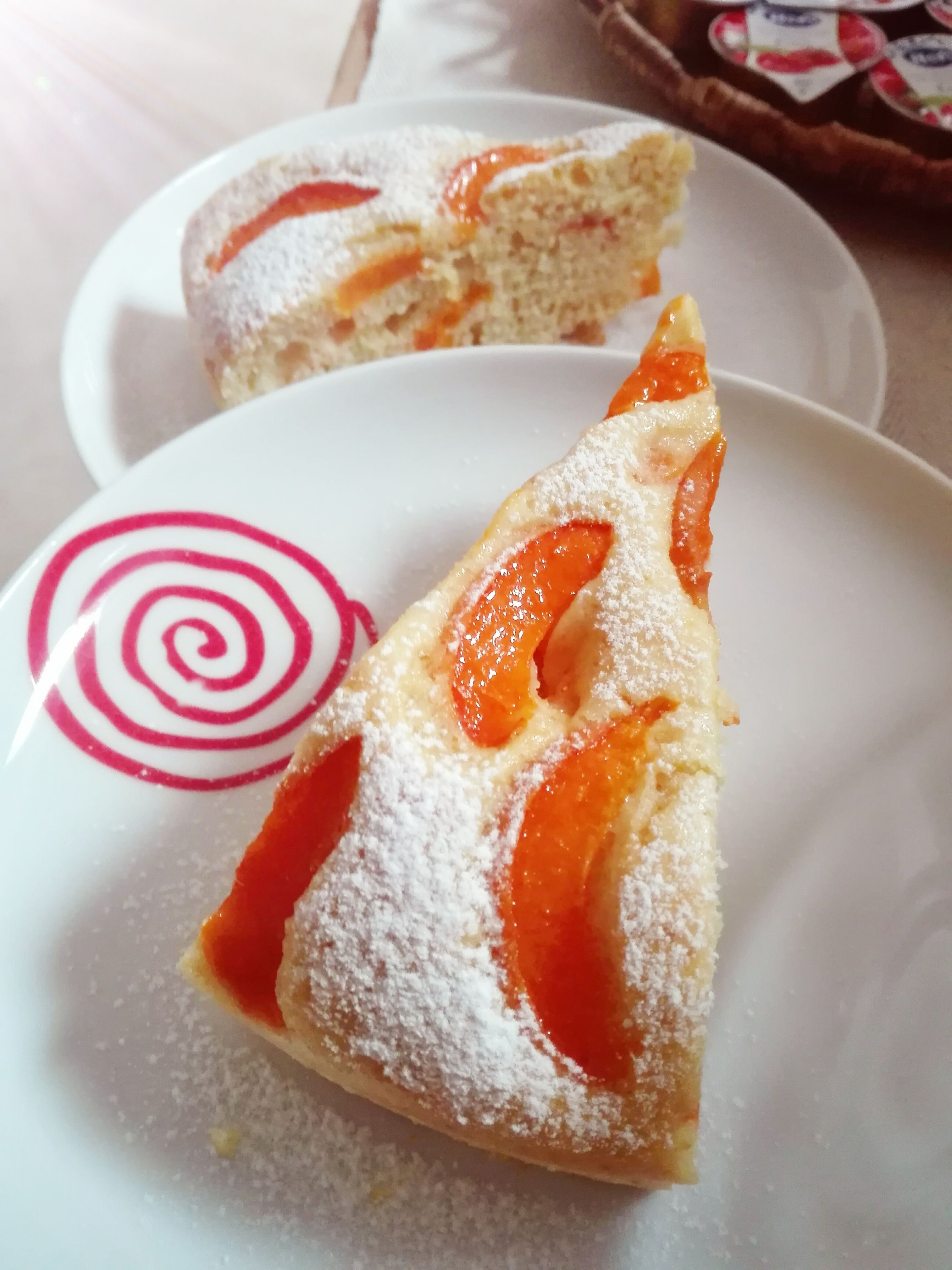 A slice of cake with powdered sugar and fruit on a plate.