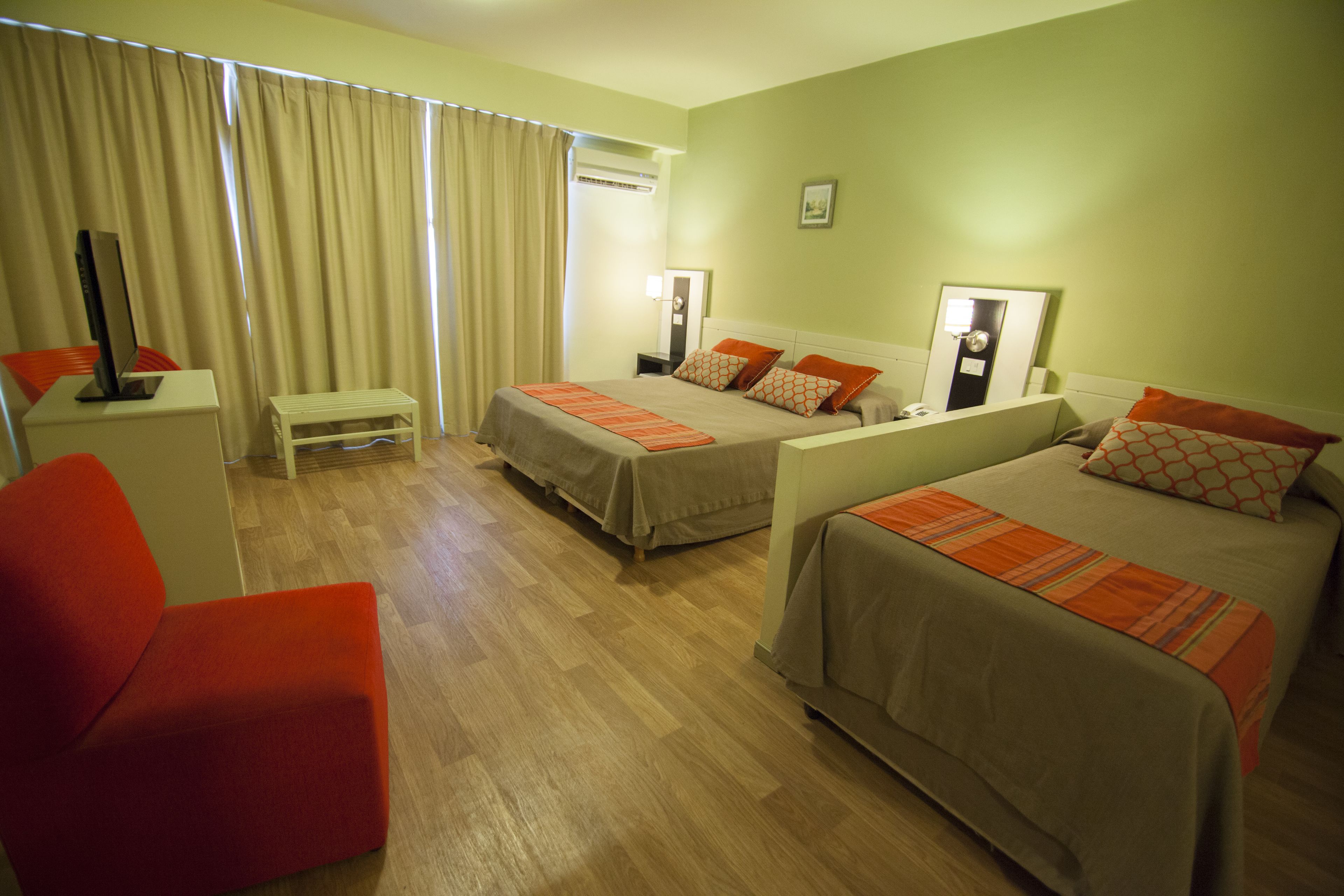 A hotel room with two beds, a desk, a chair, and a window with curtains.