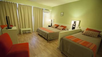 Habitación de hotel con dos camas, un escritorio, una silla y una ventana con cortinas.