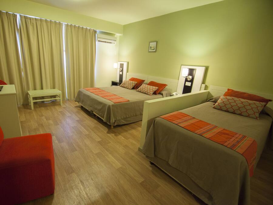 Habitación de hotel con dos camas, un escritorio, una silla y una ventana con cortinas.