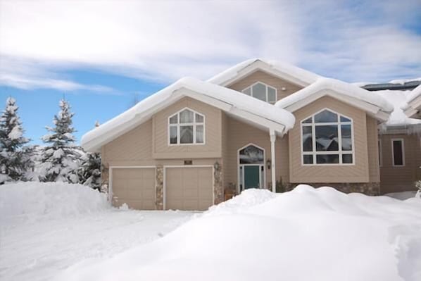 A two-story house with a garage, surrounded by snow-covered trees. - Heart of the Valley (Steamboat Springs)