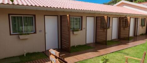 A row of single-story cabins with a tiled roof, each with a window and a door.