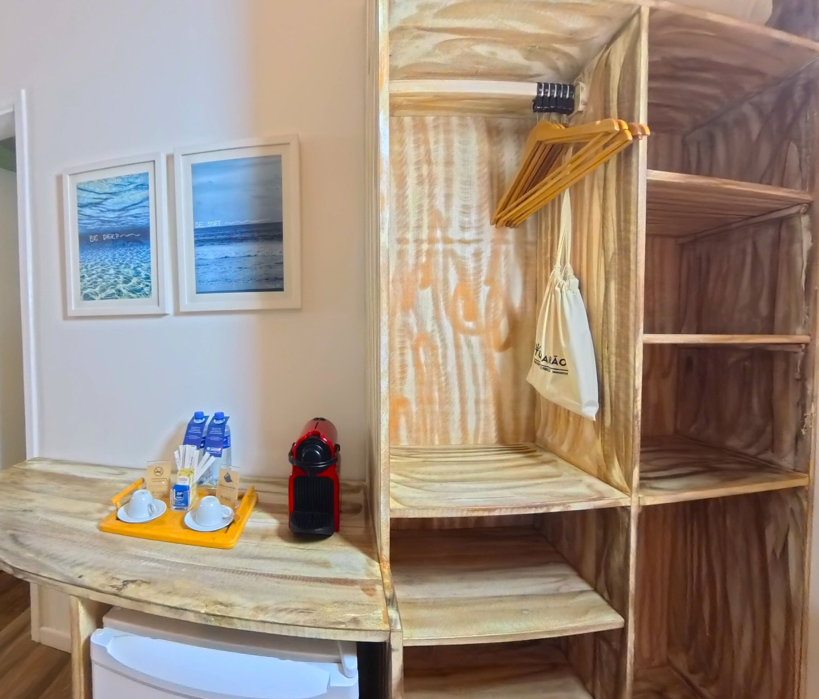 A room with a wooden shelf unit, a table with a tray of items, and two framed pictures on the wall.