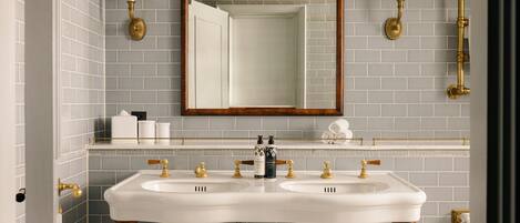 A bathroom with two sinks, a mirror, and wall-mounted lamps.