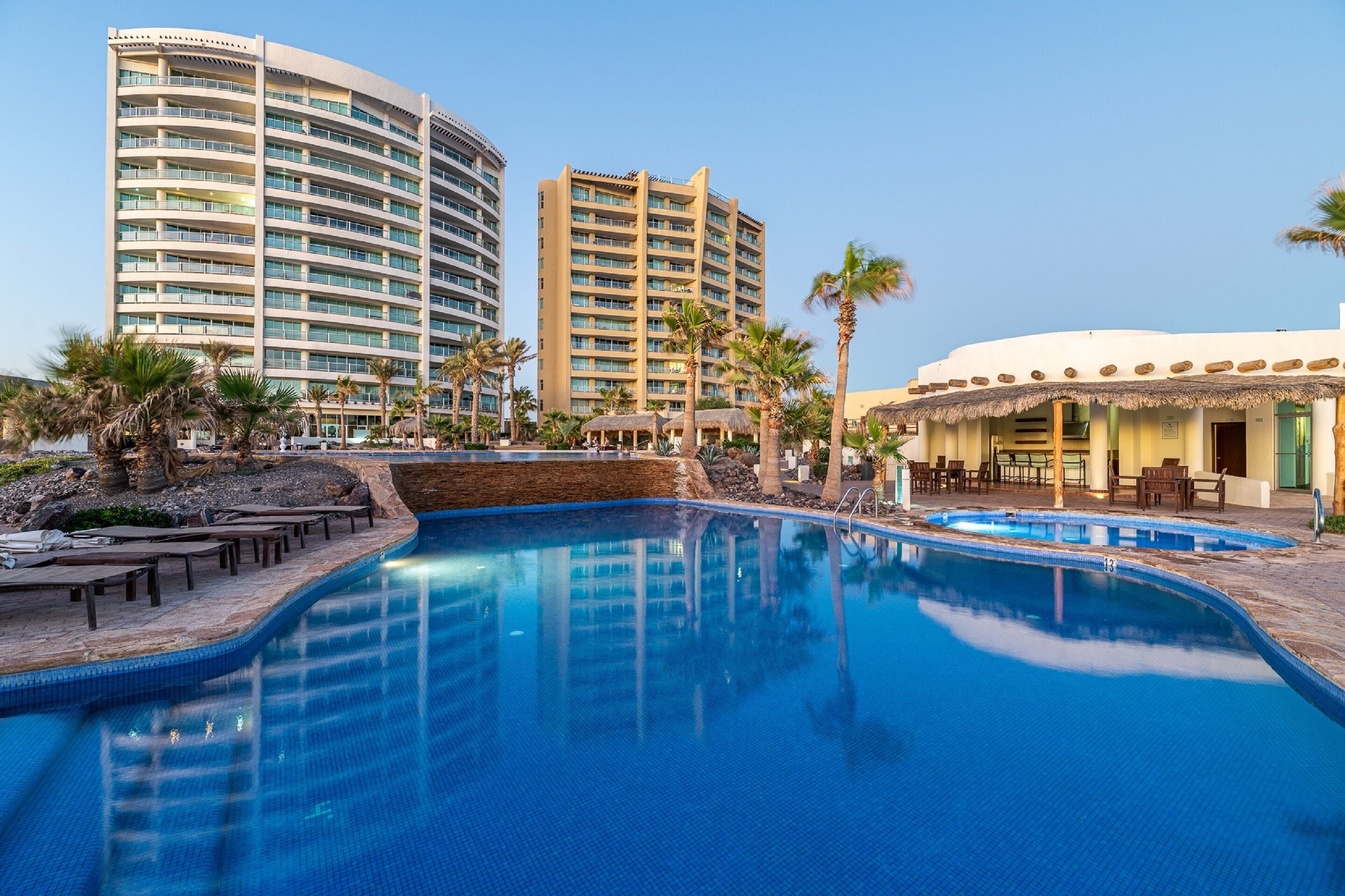 Una piscina al aire libre, sombrillas, tumbonas