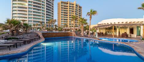 Una piscina al aire libre, sombrillas, tumbonas