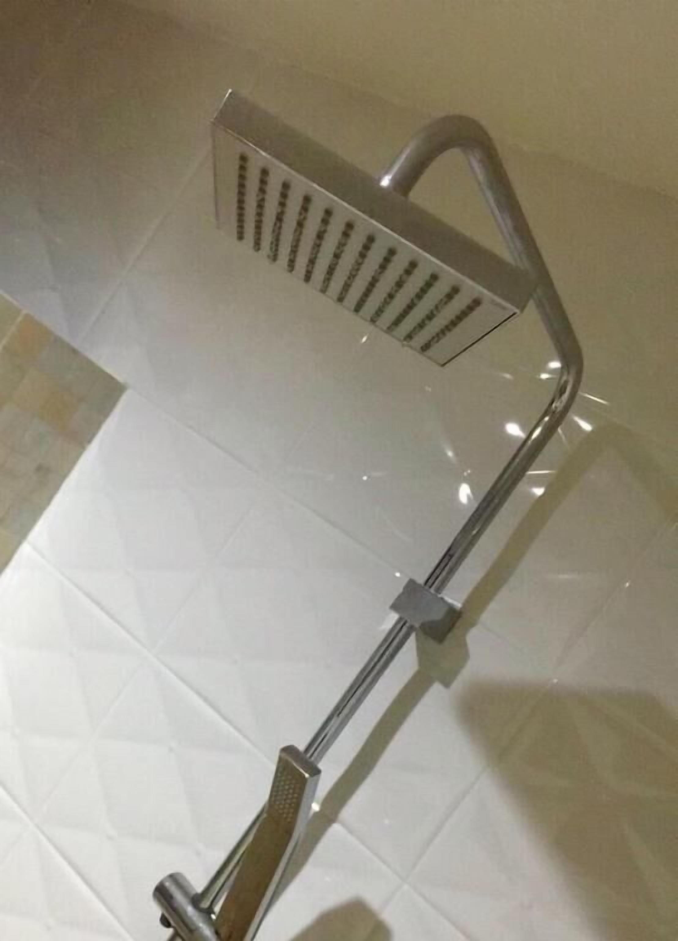 Une douche équipée d’un pommeau de douche réglable et d’une douchette fixe.