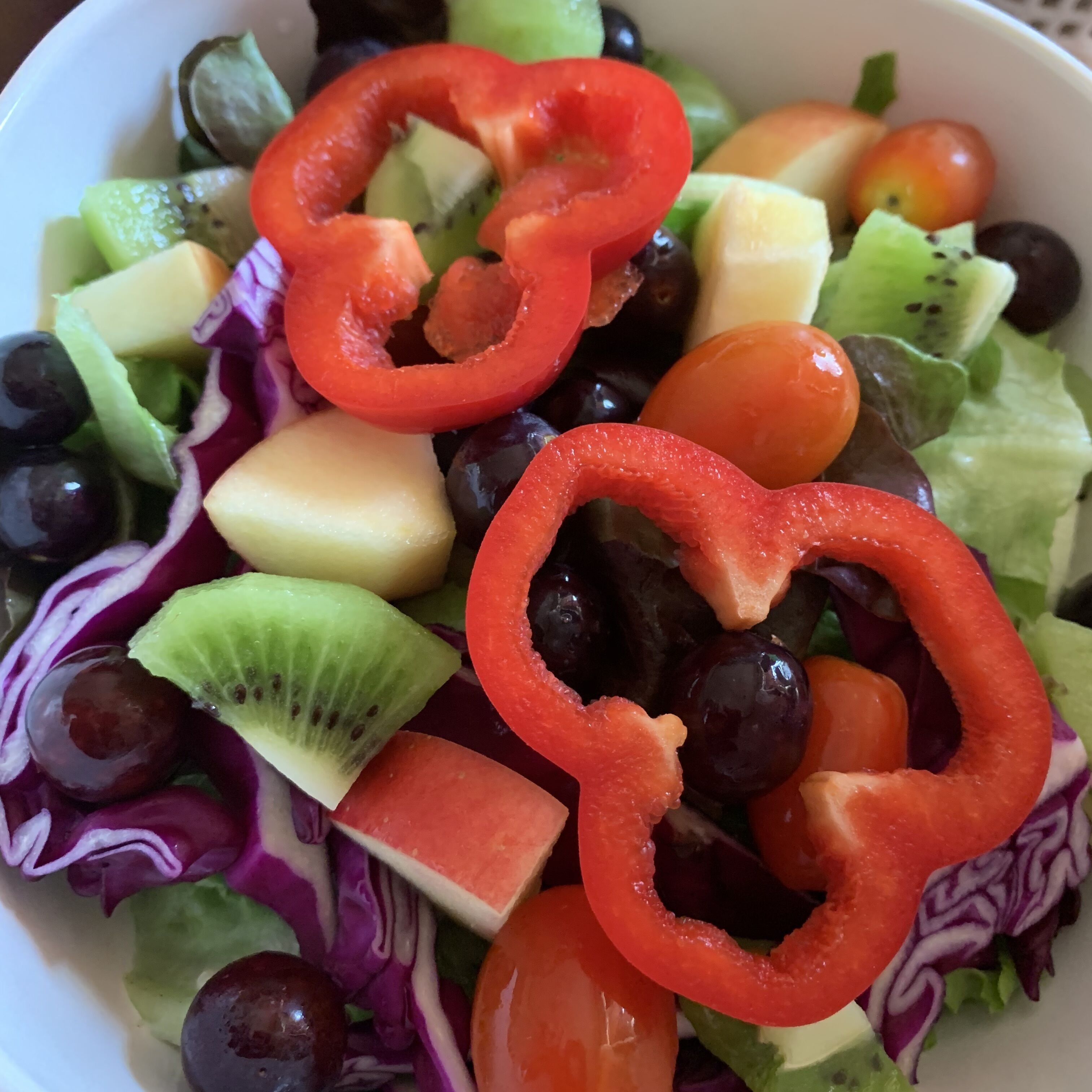 A bowl of mixed fruit salad with various fruits and vegetables.