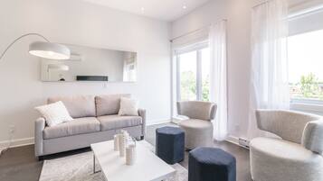 Una sala de estar moderna con un sofá, sillones, una mesa de centro y un ventanal con cortinas.
