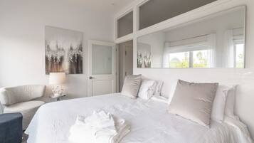 Habitación de hotel con una cama grande, una silla, una lámpara y un cuadro en la pared.