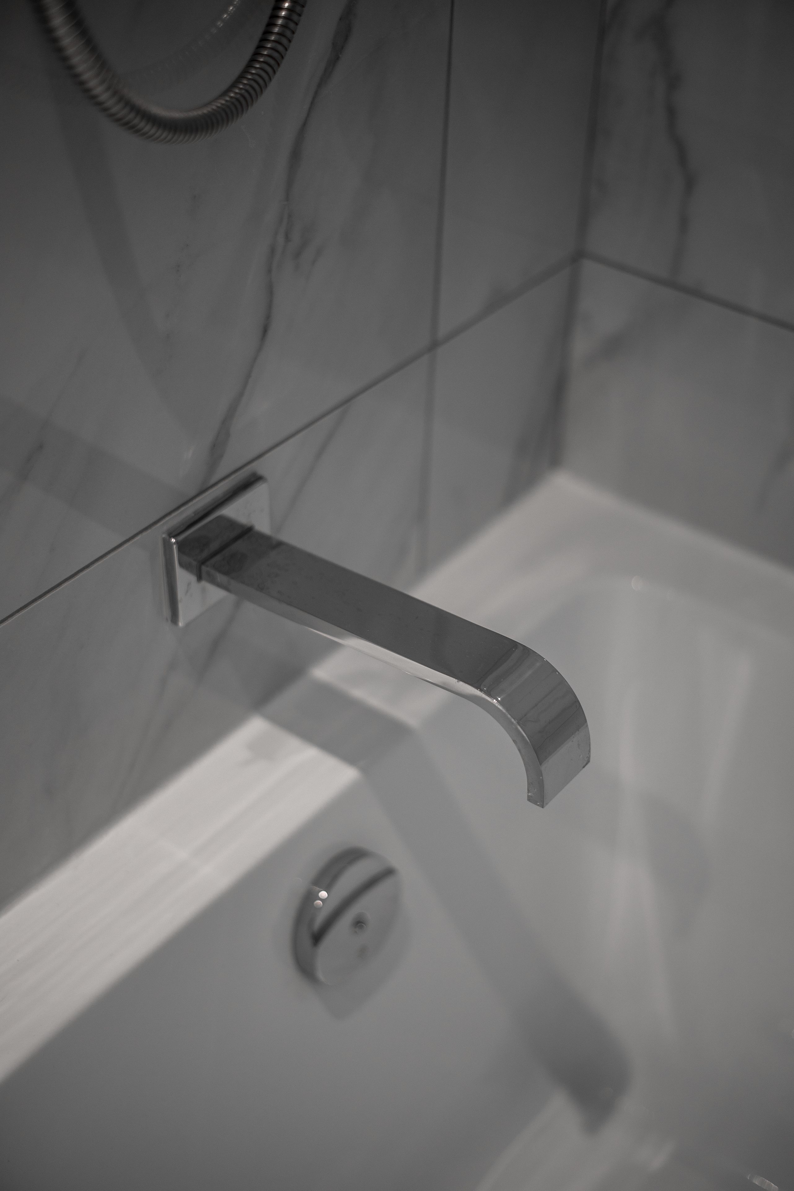 A bathroom with a modern faucet and a visible drain.