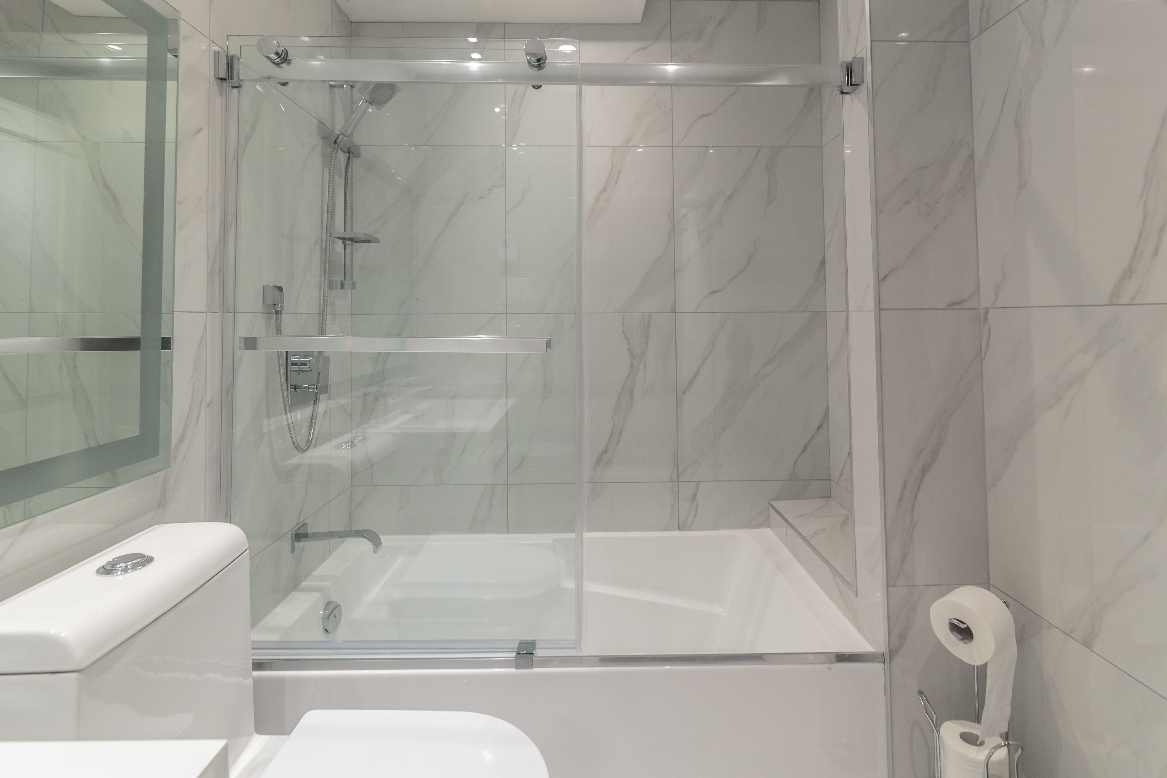 A modern bathroom with a glass-enclosed shower, a toilet, and a bidet.