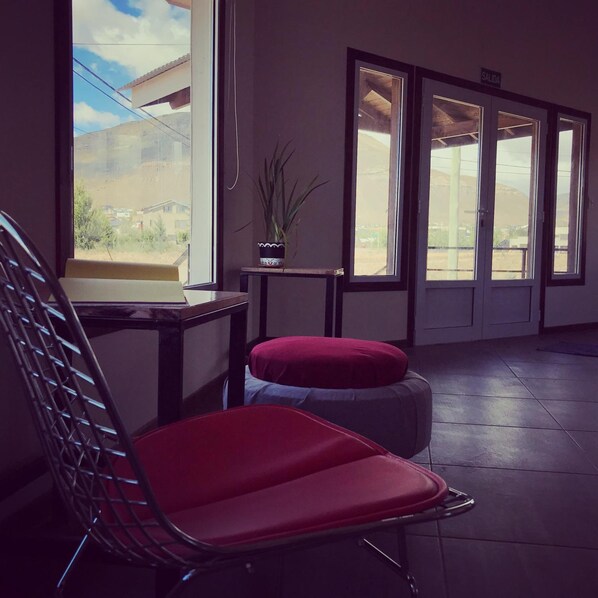 A room with a large window, a chair, a small table, and a potted plant. - Folk Hostel (El Calafate)
