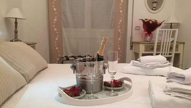 A bed with a champagne bottle, a glass, and a tray with strawberries. - 41 Duodo Vatican Relais (Rome)