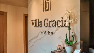 Ein Empfangsschalter mit einem Schild, auf dem 'Villa Graciel' steht, und einem Topforchidee.