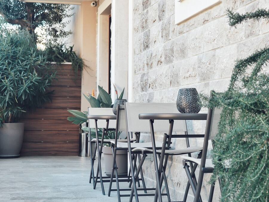 Un patio con mobiliario exterior, una pared de piedra y plantas en macetas.