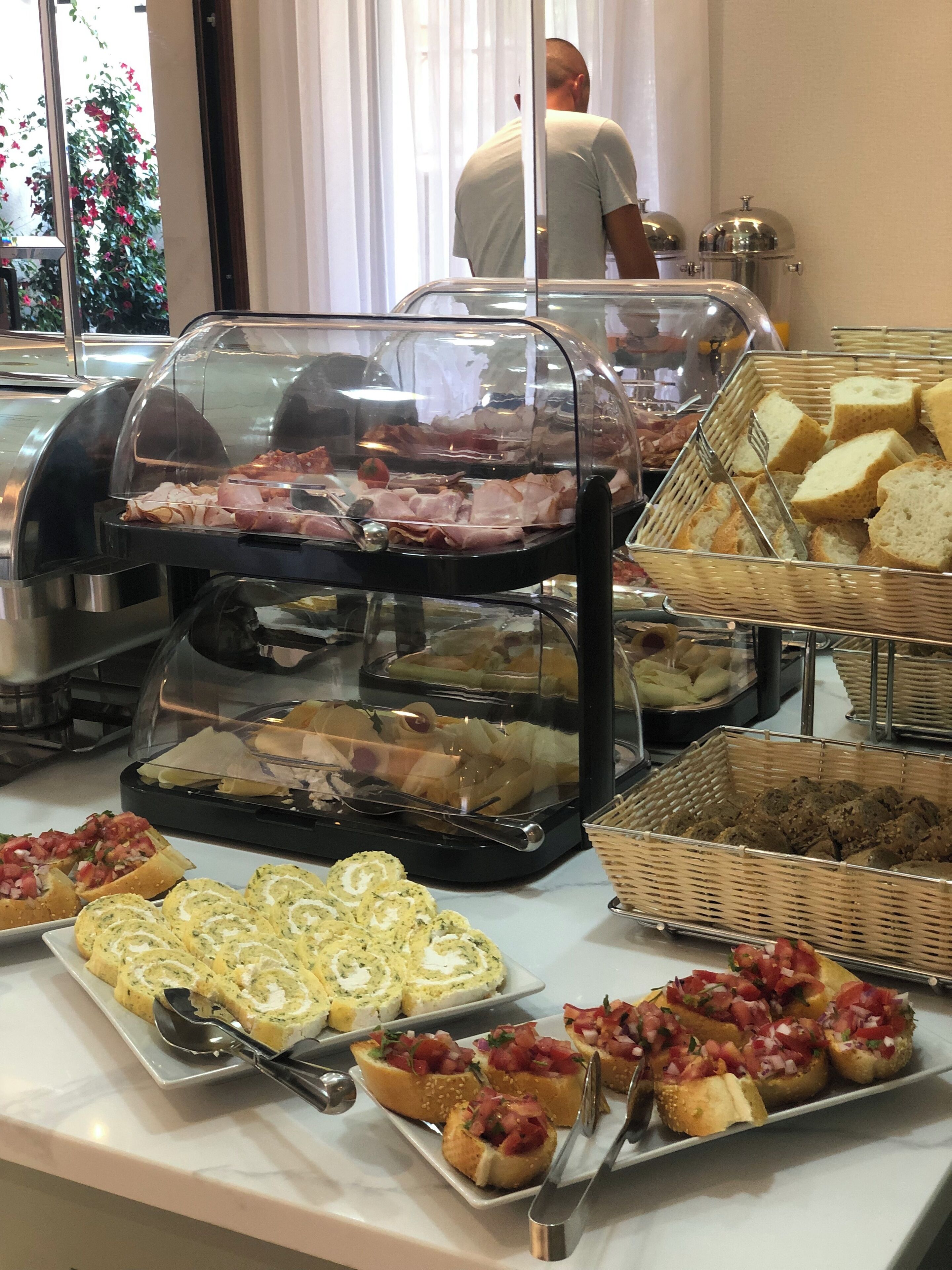 A buffet with various food items including meats, cheeses, and bread.