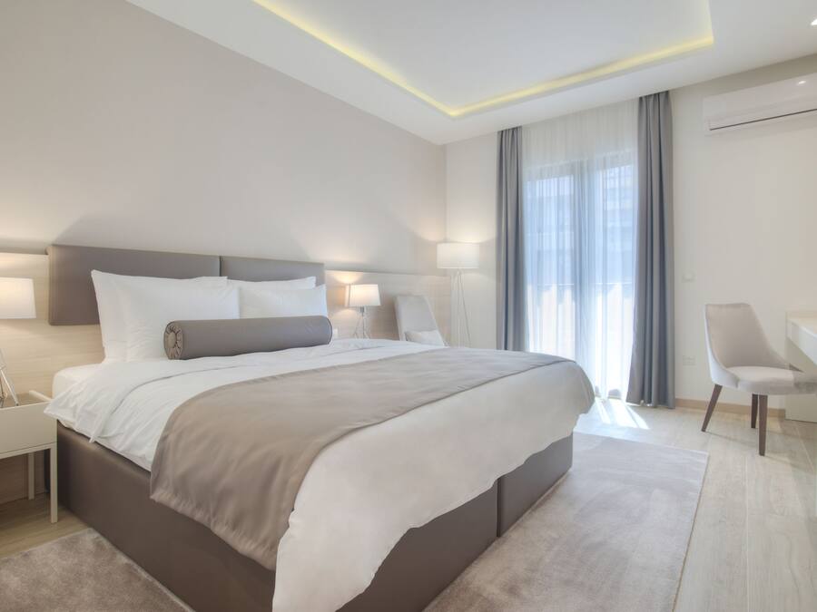 Un dormitorio de hotel moderno con una cama grande, mesitas de noche, un escritorio y una silla.