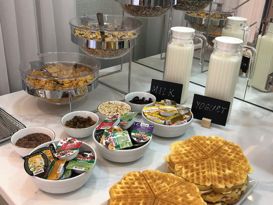 Un bufé con diversas opciones de comida, como waffles, yogur y cereales.