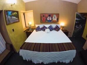Una habitación de hotel con una cama grande, una mesita de noche, una lámpara de pared y un cuadro sobre la cama.