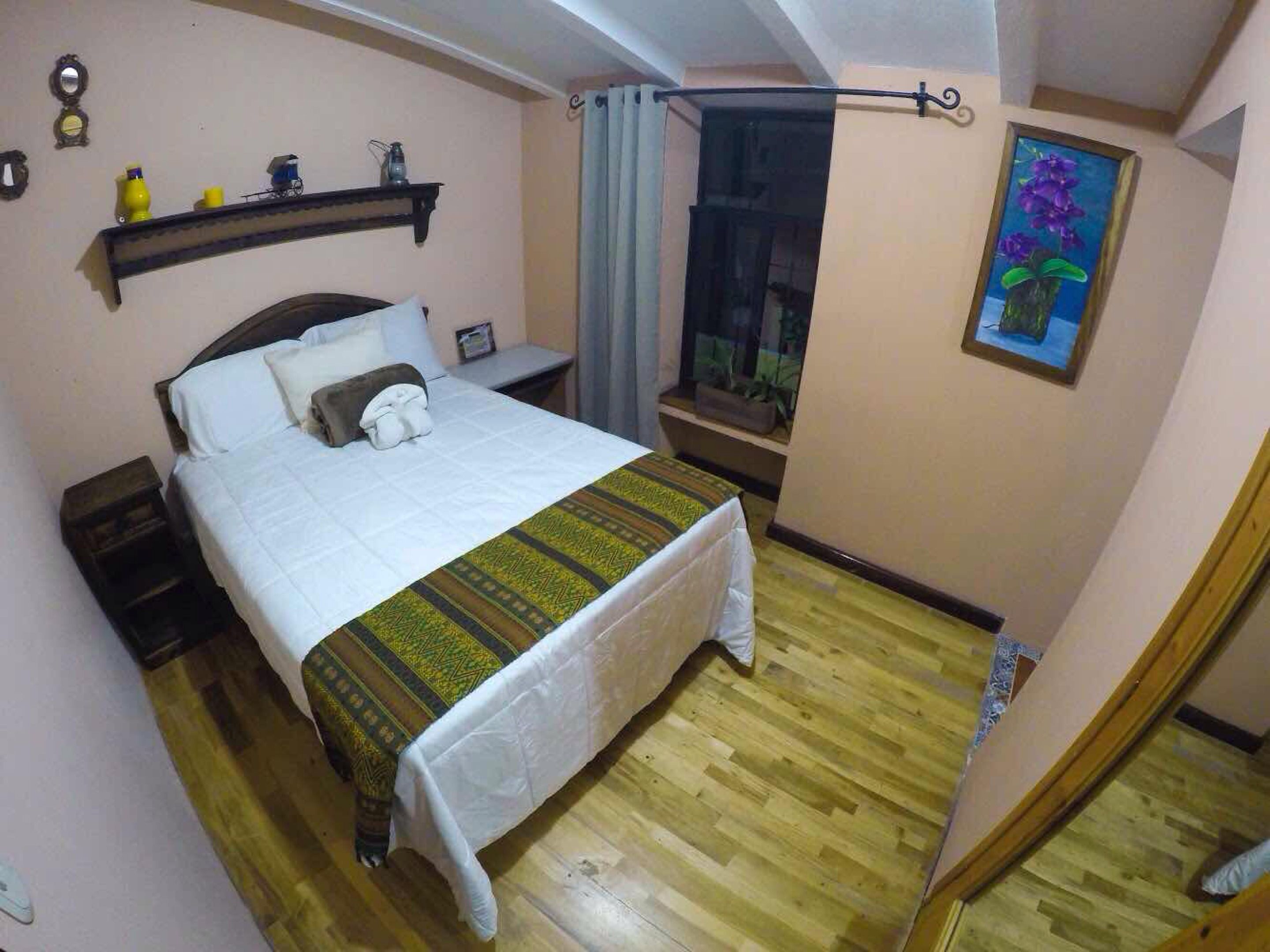 A bedroom with a bed, bedside table, and a window with curtains.