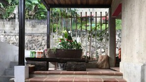 A covered outdoor area with a stone wall, a metal gate, and a wooden bench. - Hotel Casa Jose Coban (Cobán)
