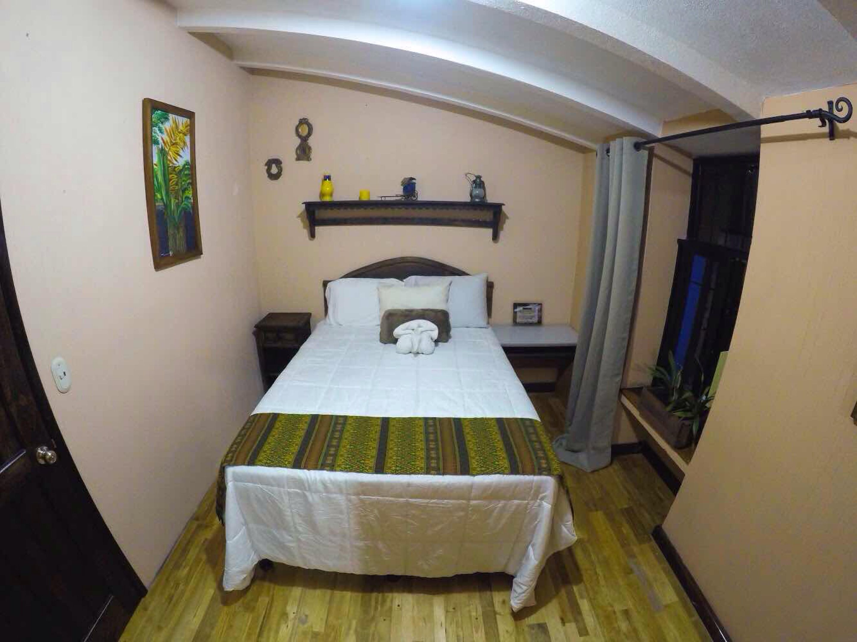 Una camera da letto con un letto, un comodino, una mensola a parete e una finestra con tende.
