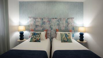 Habitación de hotel con dos camas, cada una con lámpara y almohadas decorativas.