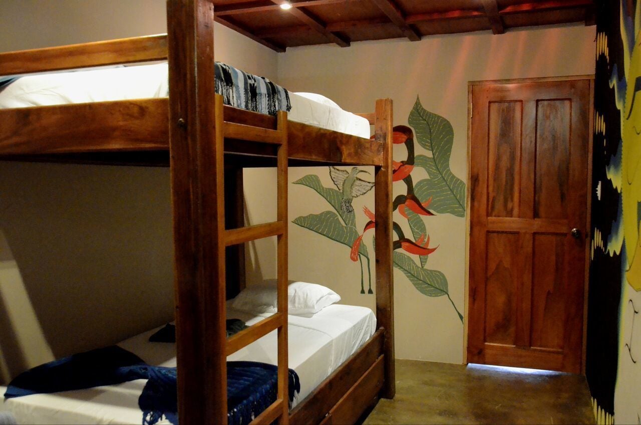A bunk bed room with a wooden door and a wall mural.