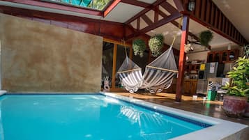 Una piscina al aire libre, sillones reclinables de piscina