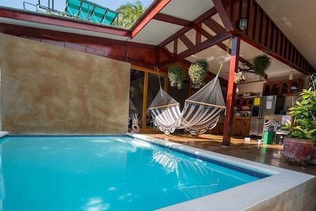 Una piscina al aire libre, sillones reclinables de piscina