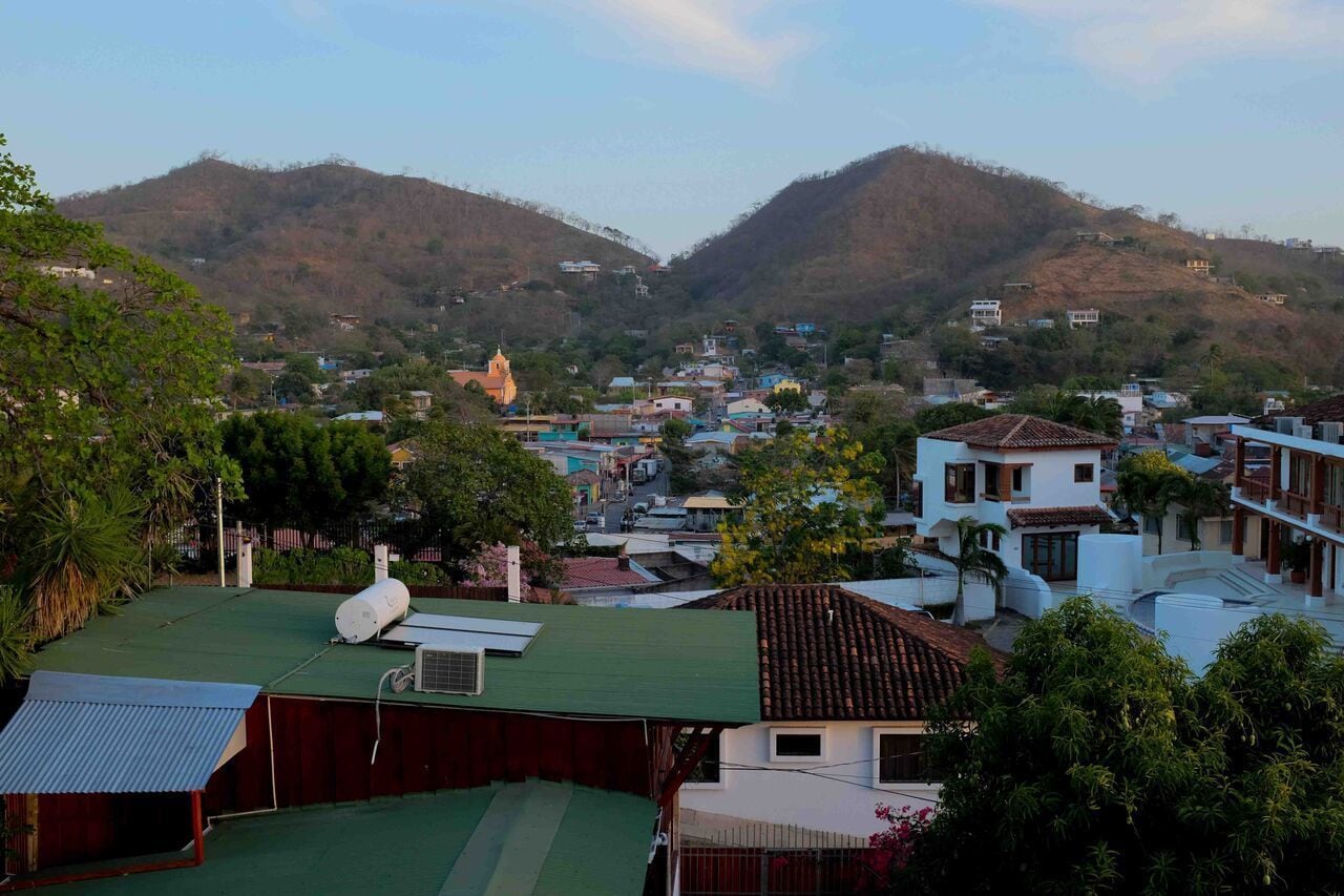 A residential area with houses, a church, and hills in the background.