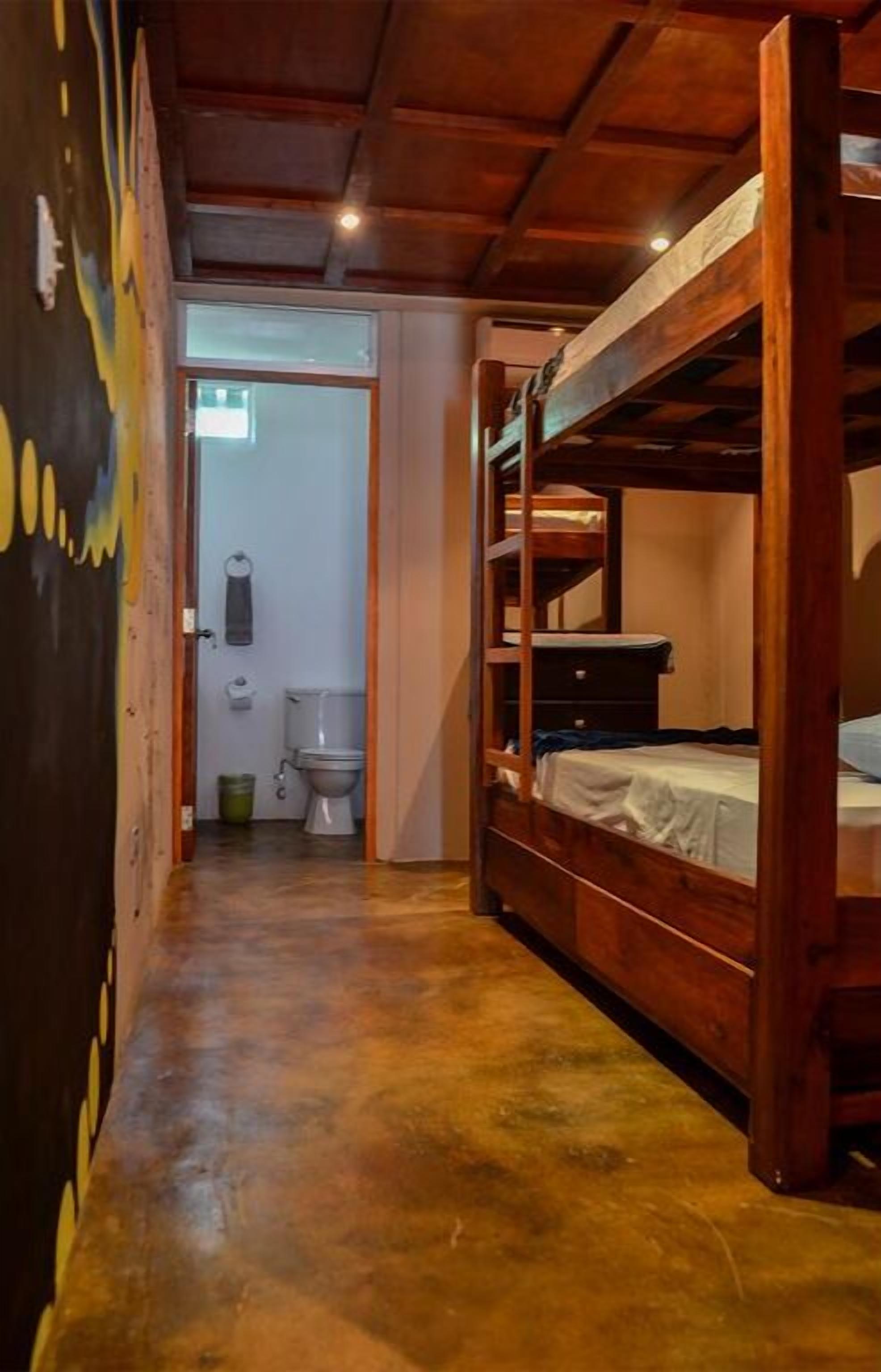 Un couloir étroit avec un lit superposé et des toilettes au fond.