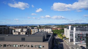 A cityscape with modern buildings, a clear sky, and distant mountains. - Thon Hotel Storo (Oslo)